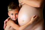 Un niño se abraza al vientre de su madre embarazada