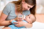 Una mujer alimenta a su bebé con un biberón con leche maternizada