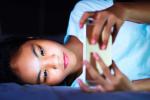 Chica con el smartphone leyendo en la cama