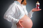 Mujer embarazada sujeta un biberón lleno de cápsulas 