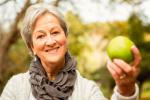 Mujer mayor sostiene una manzana