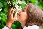 Una mujer huele las flores de una planta