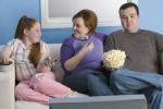 Familia de obesos viendo la tele con comida basura