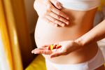 Mujer embarazada sostiene en su mano un puñado de antibióticos