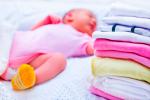 Bebé durmiendo al lado de una pila de ropa