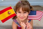 Niña sosteniendo una bandera española y otra estadounidense