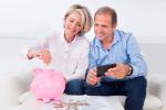 Una pareja mayor guarda dinero en una hucha