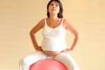 Mujer embarazada sentada sobre pelota de gimnasia