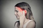 Mujer joven con tinnitus se toca la sien