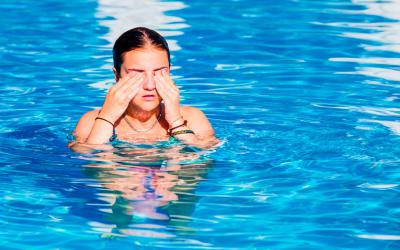 Una joven en la piscina se frota los ojos