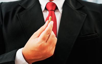 Un hombre con traje sujeta una cápsula con sus dedos