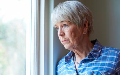 Mujer mayor deprimida mirando por la ventana