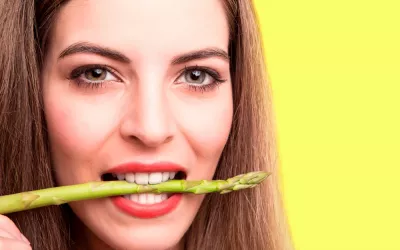 Una mujer muerde un espárrago verde