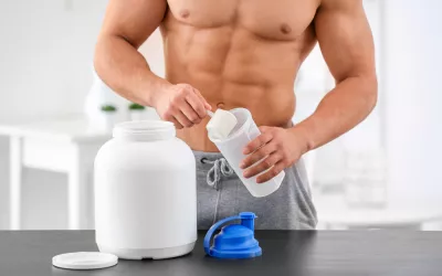 Gainers, ganadores de peso Hombre con músculos tomando suplementos para el deporte llamados gainers