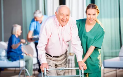 Una cuidadora ayuda a un anciano en una residencia