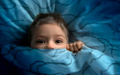 Miedo a la oscuridad en los niños NIño austado metido entre las sábanas de la cama