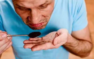 Un hombre intentando oler una cucharada de café