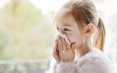 Niña resfriada se suena la nariz con un pañuelo