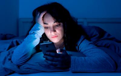 Chica joven leyendo sus redes sociales en la cama por la noche
