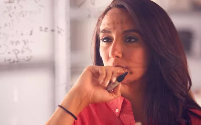 Mujer frente a un problema matemático escrito en una pizarra de metacrilato