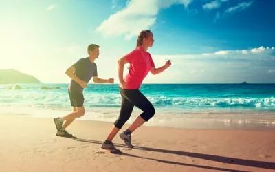 Pareja corriendo bajo el sol por la playa