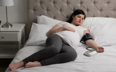 Mujer embarazada tumbada en su cama se mide la presión arterial