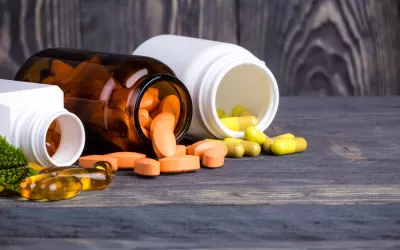Tres frascos abiertos de los que salen píldoras con suplementos dietéticos