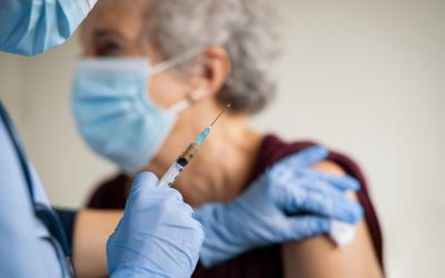 Mujer anciana vacunándose contra la gripe y el COVID