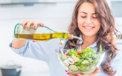 Mujer echando aceite de oliva a una ensalada