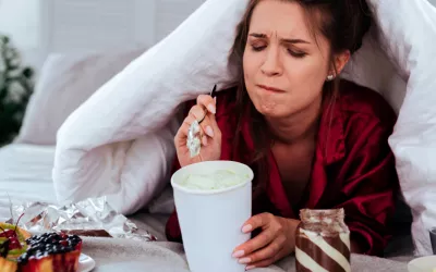 Mujer en la cama comiendo ultraprocesados
