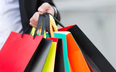 Persona adicta a las compras con la mano llena de bolsas