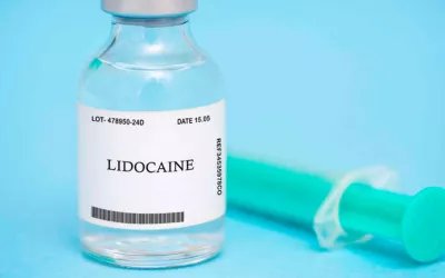Un frasco con lidocaína junto a una jeringuilla para anestesiar