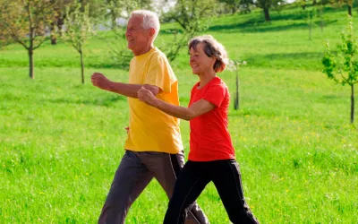 Pareja de personas mayores caminando deprisa en el parque