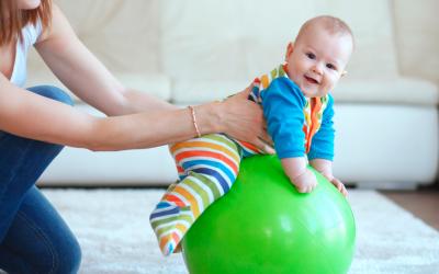 Bebé sentado sobre una pelota de goma
