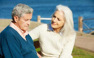Mujer consolando a su esposo sentado en un banco enfermo de alzhéimer