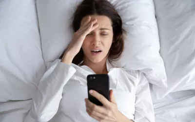 Ortosomnia, la obsesión por dormir bien que te quita el sueño Mujer mirando con angustia el dispositivo móvil creyendo que no ha dormido suficiente