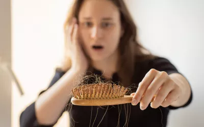 Alopecia posparto: causas, soluciones y cuándo preocuparse Mujer mirando asombrada el cepillo del pelo lleno de cabello