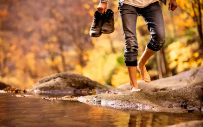 Earthing o grounding, beneficios de caminar descalzo Hombre caminando descalzo por la orilla de un río