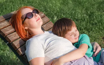 Qué es el apego y cómo se desarrolla Niño pequeño abrazado a su madre mientras están tumbados