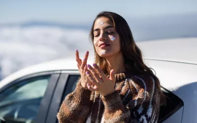 Mujer joven aplicándose protector solar en las mejillas