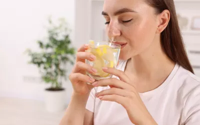 Mujer bebiendo un vaso de agua tibia con limón