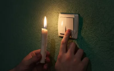 Un hombre intenta encender un interruptor con una vela en la otra mano