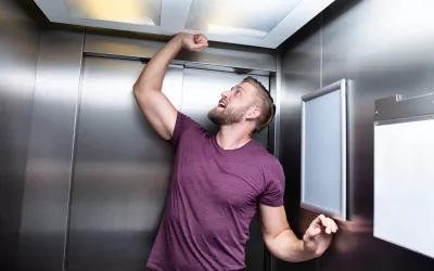 Hombre atrapado en un ascensor con signos de estrés