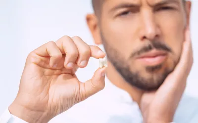 Hombre sujeta en su mano una muela del juicio recién extraída con dolor