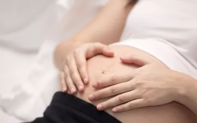 Embarazada recostada con las manos sobre el vientre