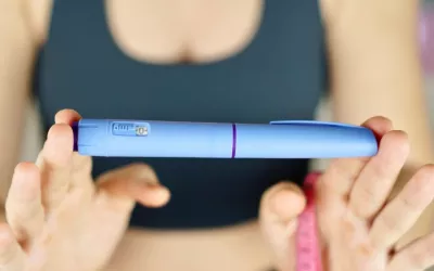 Mujer muestra una pluma de Ozempic y una cinta métrica Una mujer con ropa deportiva sujeta una pluma con semaglutida