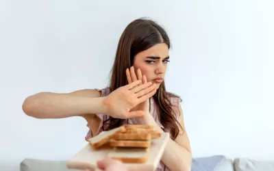 Mujer joven rechaza rebanadas de pan con gesto preocupado Una joven hace gesto de rechazo cuando le ofrecen rebanadas de pan