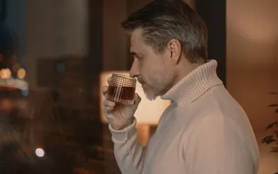 Hombre a punto de tomarse un whisky en su casa