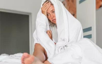 Mujer de mediana edad sentada en la cama con gesto preocupado