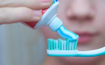 Un joven poniendo un poco de pasta de dientes sobre el cepillo dental